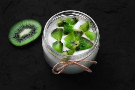 Yogurt with kiwi slices on a black background.の写真素材