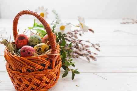 Easter eggs in a basket on a white wooden background.の写真素材