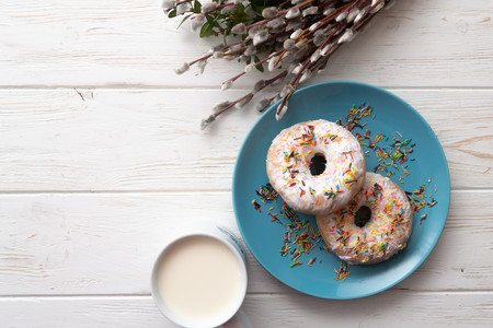 Donuts on a white wooden background with a cup of milk and willow twigs.の写真素材