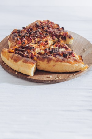 Homemade pizza on white wooden background on kitchen board.の写真素材