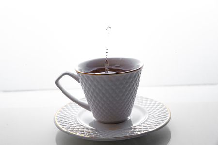 Tea splashes in a cup on a white background.の写真素材