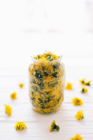 Dandelions in a glass jar on a white background.の写真素材