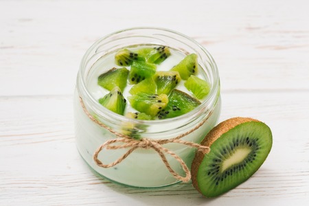 Yogurt with kiwi slices on a wooden white backgroundの写真素材