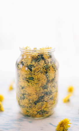 Dandelions in a glass jar on a white background.の写真素材