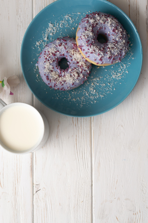 Donuts on a blue plate with a cup of milk on a white wooden background.の写真素材