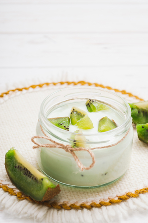 Yogurt with kiwi slices on a wooden white backgroundの写真素材