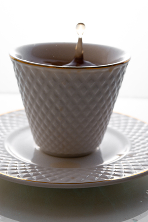 Tea splashes in a cup on a white background.の写真素材