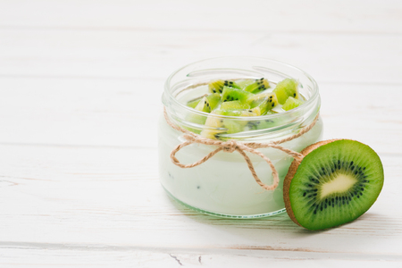 Yogurt with kiwi slices on a wooden white backgroundの写真素材