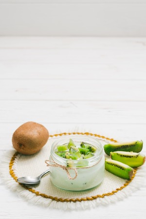 Yogurt with kiwi slices on a wooden white backgroundの写真素材
