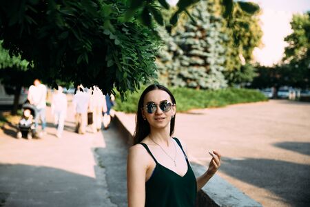 Brunette girl in a summer day in the city wearing round sunglasses.の写真素材