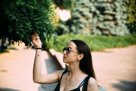 Brunette girl in a summer day in the city wearing round sunglasses.の写真素材