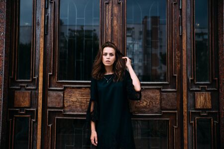 Young girl in green dress near old big building door.の写真素材