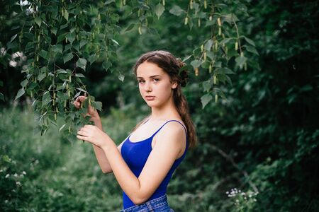 Beautiful girl in short shorts and a blue T-shirt in the woods.の写真素材