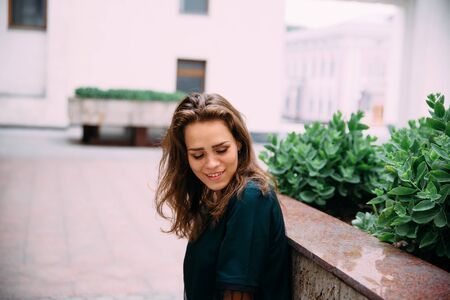 Young girl in a green dress near a stone wall with plants.の写真素材