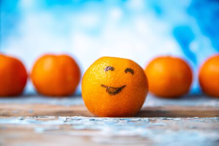 Tangerines with painted eyes on blurred wooden backgroundの写真素材