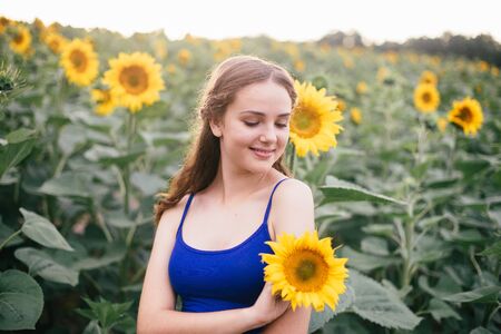 Beautiful girl on the field with sunflowers in short shorts and a vest.の写真素材