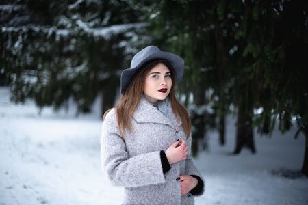 Girl in a gray coat in a winter snow park.の写真素材