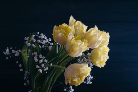 Yellow tulips in a vase on a wooden background.の写真素材