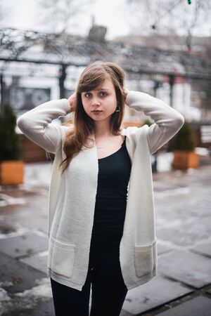 Girl in winter in a cardigan on a street in the city.の写真素材