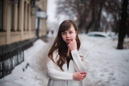 Girl in winter in a cardigan on a street in the city.