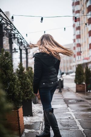 Girl in winter in a cardigan on a street in the city.の写真素材