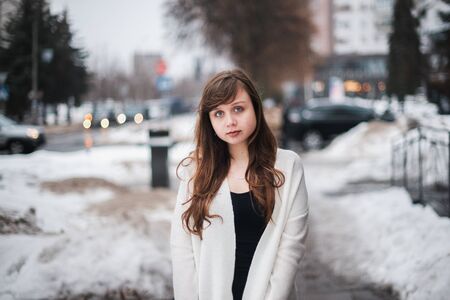 Girl in winter in a cardigan on a street in the city.の写真素材