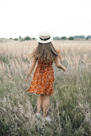 Girl in a red dress on a wheat field.の写真素材