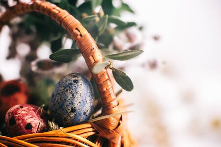 Easter eggs in a basket on a white wooden background.