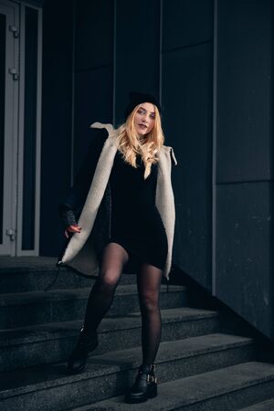 Girl in a black dress in the winter on a background of a dark building.の写真素材