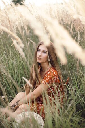 Girl in a red dress on a wheat field.の写真素材