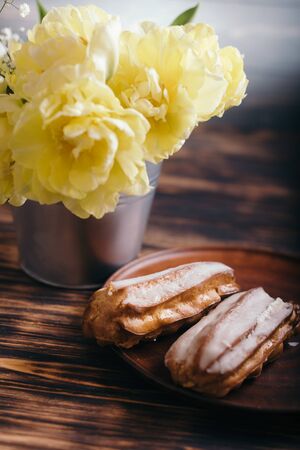 Choux cake on a wooden background with tulips.の写真素材