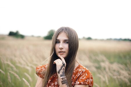 Girl in a red dress on a wheat field.の写真素材