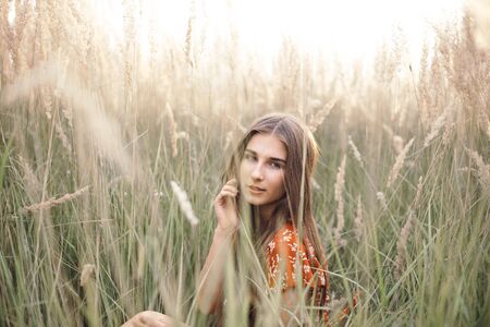 Girl in a red dress on a wheat field.の写真素材