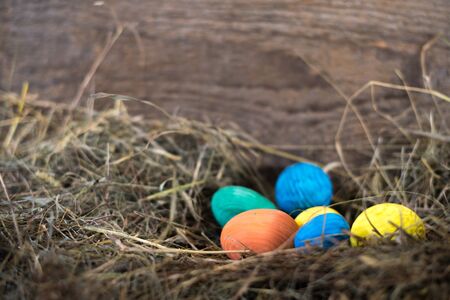Easter eggs in a basket on a hay with a blurred background.の写真素材