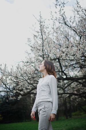 Beautiful young girl is resting and enjoying spring in the spring park.の写真素材