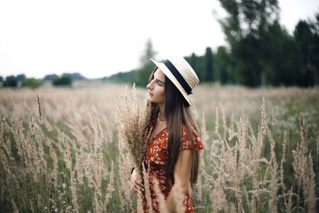 Girl in a red dress on a wheat field.の写真素材