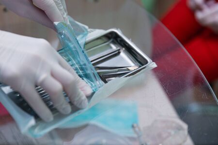 Dental appliances in sterile packaging. Dentist's hand in glovesの写真素材
