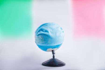 Globe in a medical mask with the flag of Italy. World pandemic concept.の写真素材