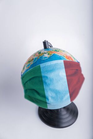 Globe in a medical mask with the flag of Italy. World pandemic concept.の写真素材