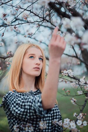 Beautiful young blonde girl on a background of flowering trees.の写真素材