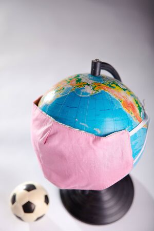 Globe in a medical mask with a soccer ball.の写真素材