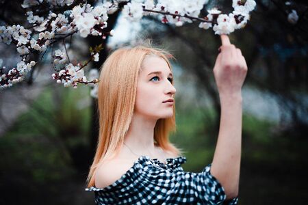 Beautiful young blonde girl on a background of flowering trees.の写真素材