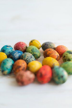 Multi-colored quail Easter eggs on a white wooden background.の写真素材