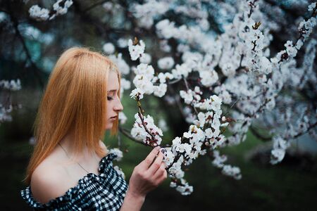 Beautiful young blonde girl on a background of flowering trees.の写真素材