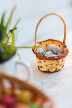 Multi-colored Easter eggs in a basket on a white wooden background.の写真素材