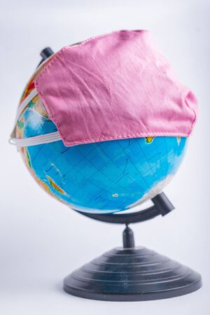 Globe in a medical mask on a light blurry background. Coronavirus pandemic protection concept.の写真素材