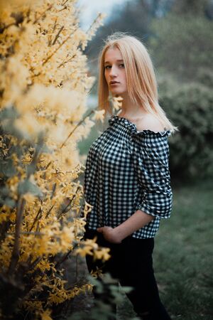 Beautiful young blonde girl on a background of flowering trees.の写真素材