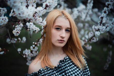 Beautiful young blonde girl on a background of flowering trees.の写真素材