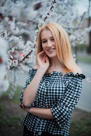 Beautiful young blonde girl on a background of flowering trees.の写真素材