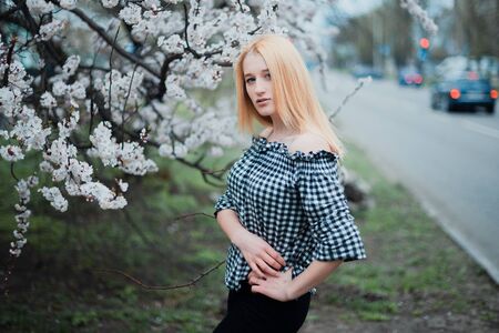 Beautiful young blonde girl on a background of flowering trees.の写真素材